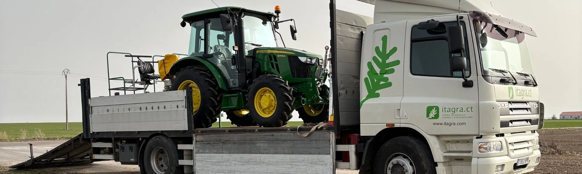 Camión de ITAGRA.CT transportando un tractor y maquinaria agrícola para realizar ensayos, investigación y experimentación en campo.