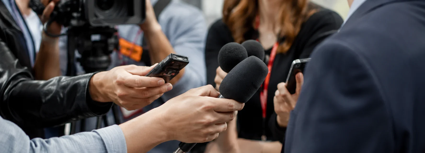 Periodistas con micrófonos, cámaras y grabadoras durante una entrevista para medios de comunicación y prensa.